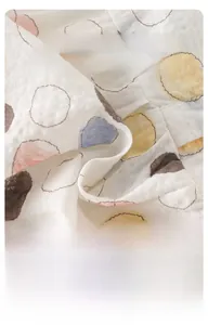 Breathable muslin baby onesie fabric detail with colorful polka dot patterns