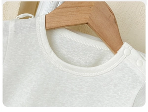 Close-up of white baby shirt featuring breathable slub cotton texture and shoulder buttons
