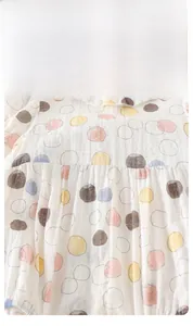 Detail of baby cotton bodysuit with colorful polka dots and a ruffled neckline trim
