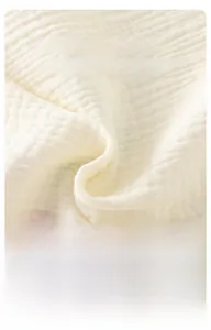 Detailed macro view of soft white pleated cotton muslin fabric with breathable texture