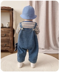 Détail de l'ensemble salopette bébé dinosaure avec t-shirt rayé et chapeau bleu
