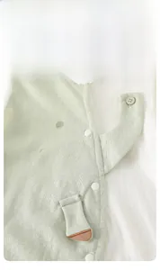 Detail of baby romper featuring mint green fabric with a cute 3D elephant button design