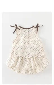 Detailed view of baby girl summer floral set featuring lace-up shoulder bows and buttons