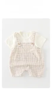 Detailed flat lay of baby summer set with white t-shirt and brown plaid overalls