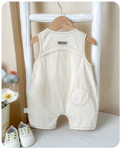 Detail of cream baby romper featuring a stylish back pocket and brand label on soft cotton