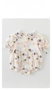 Detail of baby bodysuit with ruffle collar and colorful polka dot prints on white fabric