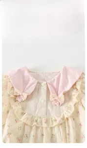 Détail de barboteuse bébé fille à fleurs avec col en dentelle rose et petit nœud
