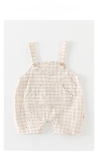 Detail of baby cotton overalls with bear pattern, wooden buttons and snap crotch
