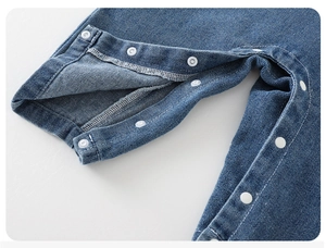 Détail des boutons-pression et du tissu denim d'une tenue bébé motif dinosaure