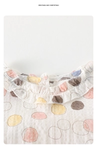 Detail of breathable muslin cotton baby bodysuit with colorful dots and ruffled collar