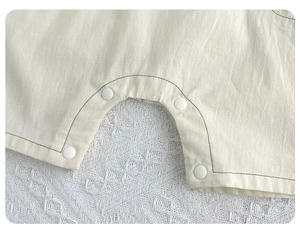 Detailed macro view of high-quality resin snap buttons on organic cotton baby romper