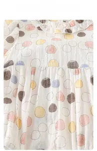 Detail of breathable white crinkle cotton baby onesie with colorful polka dot pattern