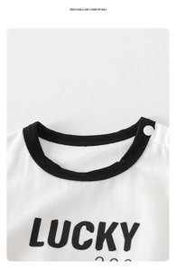 Close-up of white cotton baby bodysuit with black lucky print and shoulder snap button