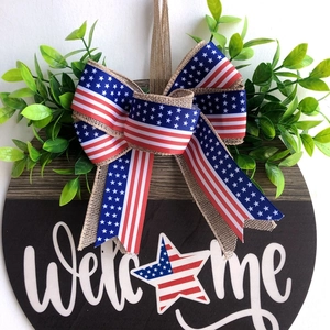 Close-up of wooden welcome sign with Independence Day bow and artificial greenery