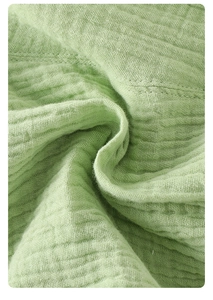 Close-up of breathable light green cotton muslin fabric with soft natural crinkle texture