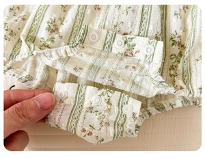 Detail of floral baby bodysuit featuring seersucker texture and snap buttons for diapering