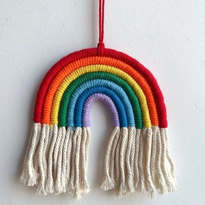 Detail of bohemian rainbow wall hanging with colorful cotton cords and cream tassels