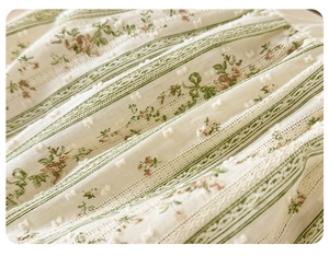 Detailed macro shot of baby romper fabric featuring green stripes and floral embroidery