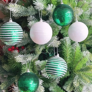 Close-up of sparkling sequined Christmas ball ornaments with silver hanging strings on a tree