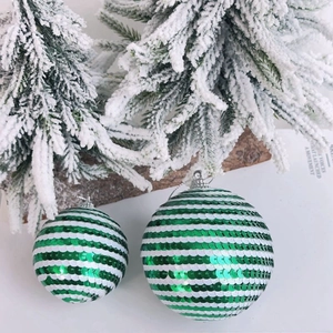 Detail of green and white sequin Christmas ball ornaments on snowy pine branches