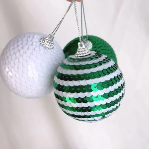 Close-up of sparkling Christmas ornaments with green and white sequins and hanging loops