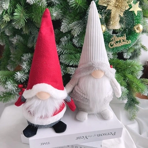 Detailed view of two Christmas gnomes with white beards on books in front of a festive tree