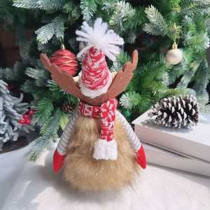 Christmas reindeer plush decoration with red knit hat and scarf by festive tree