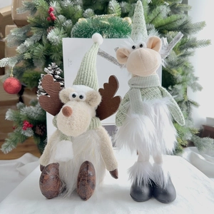 Detail of Christmas reindeer plush toys with light green knit hats and scarves on tree background