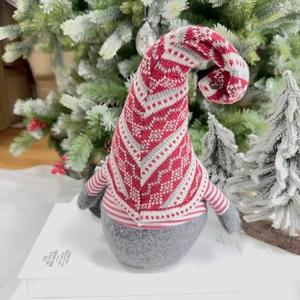 Detail of red and white knitted Nordic Christmas gnome with thick grey felt body on a book