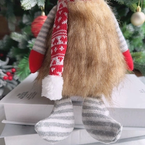 Detail of Christmas gnome plush doll with brown faux fur and red knitted scarf