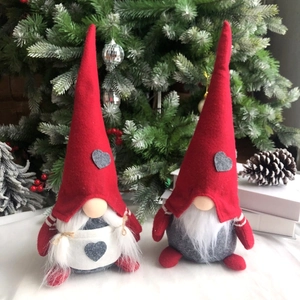 Dettaglio di coppia di gnomi natalizi in peluche con cappelli rossi e cuori grigi su libri