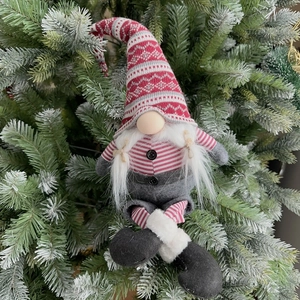 Detail of a 60cm Christmas gnome plush with knit hat and braids hanging on a tree