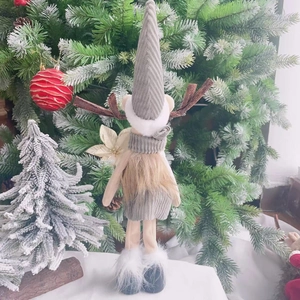 Cute Christmas reindeer doll with long knit hat and faux fur boots on a festive tree background