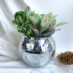 Macro detail of disco ball planter with realistic artificial green foliage and mirror tiles