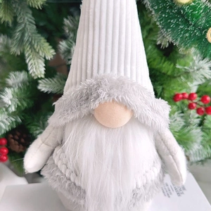Close-up of a white corduroy Christmas gnome with a long faux fur beard and festive pine cones