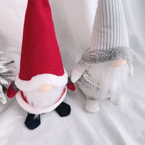 Detail of Christmas faceless gnomes with red and grey striped hats on white fabric