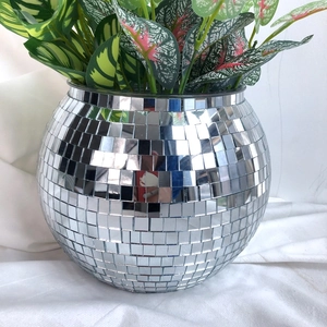 Close-up of a silver mosaic disco ball planter with artificial green and pink leaves