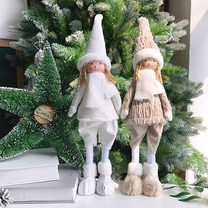 Close-up of plush Christmas elf dolls with long legs and knitted hats near a tree
