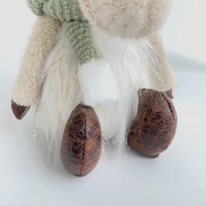 Detail of plush Christmas gnome showing soft white fur and mint green knitted scarf texture