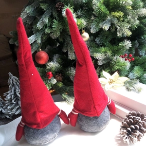 Dettaglio di due gnomi natalizi con cappelli rossi e braccia a righe vicino all'albero
