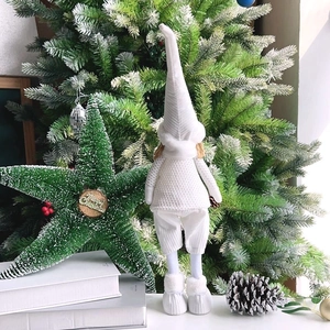 Detail of a plush Christmas gnome with a long white hat in a festive holiday setting