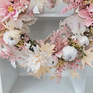 Détail d'une couronne de dahlias roses et citrouilles blanches sur treillis blanc