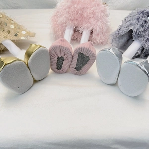 Detail view of doll base feet in gold sequins, pink plush, and silver metallic finishes