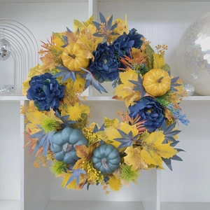 Detailed shot of autumn wreath with blue peonies, yellow pumpkins and maple leaves