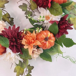 Autumn wreath with pumpkins, red dahlias and lilies for Halloween door decoration