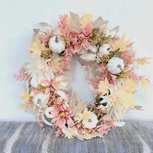 Détail d'une couronne d'automne avec dahlias roses, citrouilles blanches et érables
