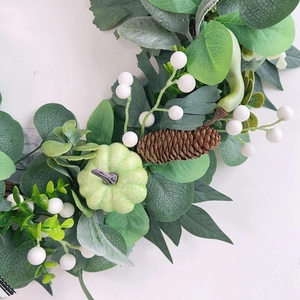 Autumn wreath with green leaves, mini pumpkins, pine cones and white berries for wall decor