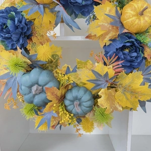 Detailed close-up of blue pumpkin autumn wreath with maple leaves and peonies