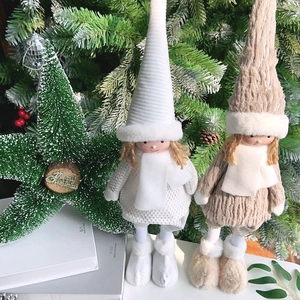 Detailed view of two plush long-legged Christmas angel dolls standing by a festive tree
