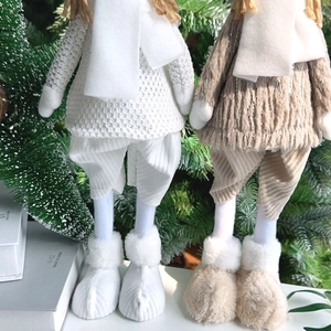 Close-up of plush Christmas angel dolls with knit sweaters and thick faux fur boots